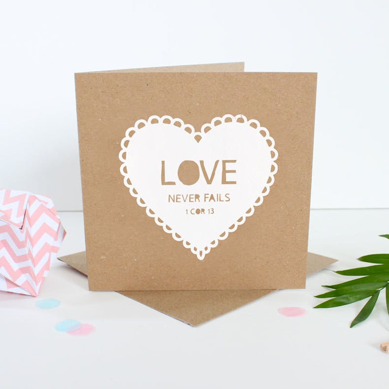 Brown kraft card with white paper cut out heart with words Love never fails by Kiwi Tree Designs | Cheerfully Given