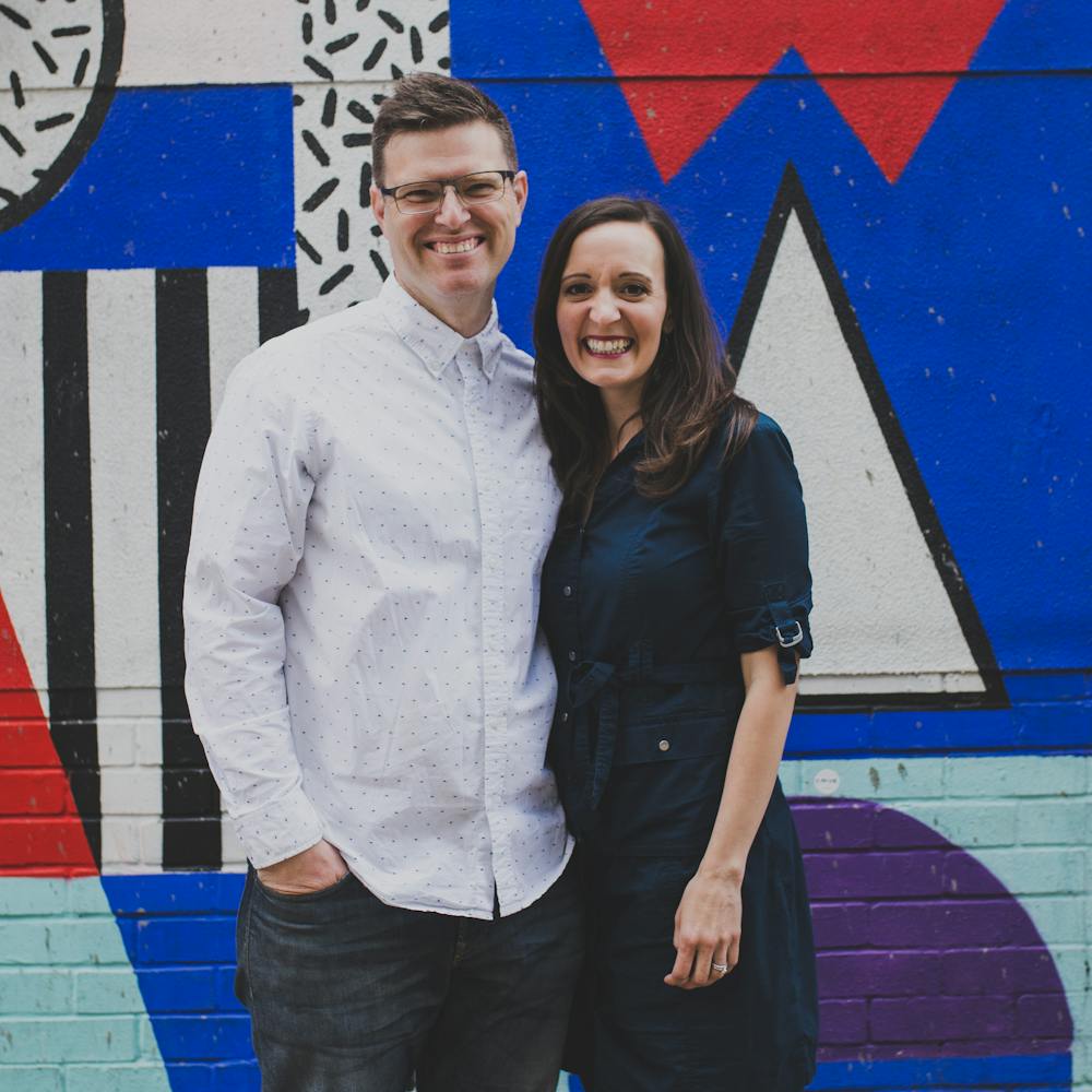 Maya & Patrick Laurent of Laurent Collective stand smiling before a graffiti art decorated wall | Cheerfully Given