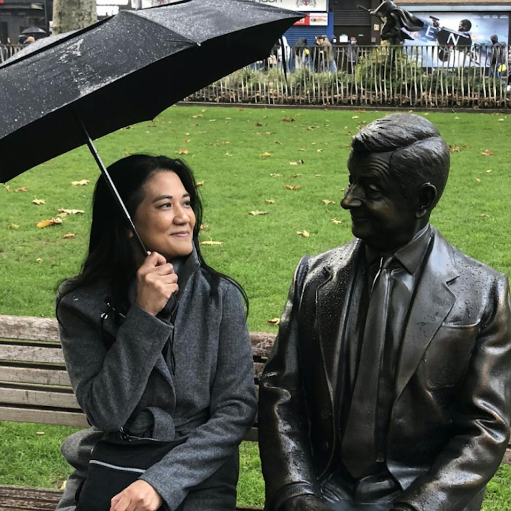 Ann Tuitt of WonderfulPrints sits on a bench with an umbrella | Cheerfully Given