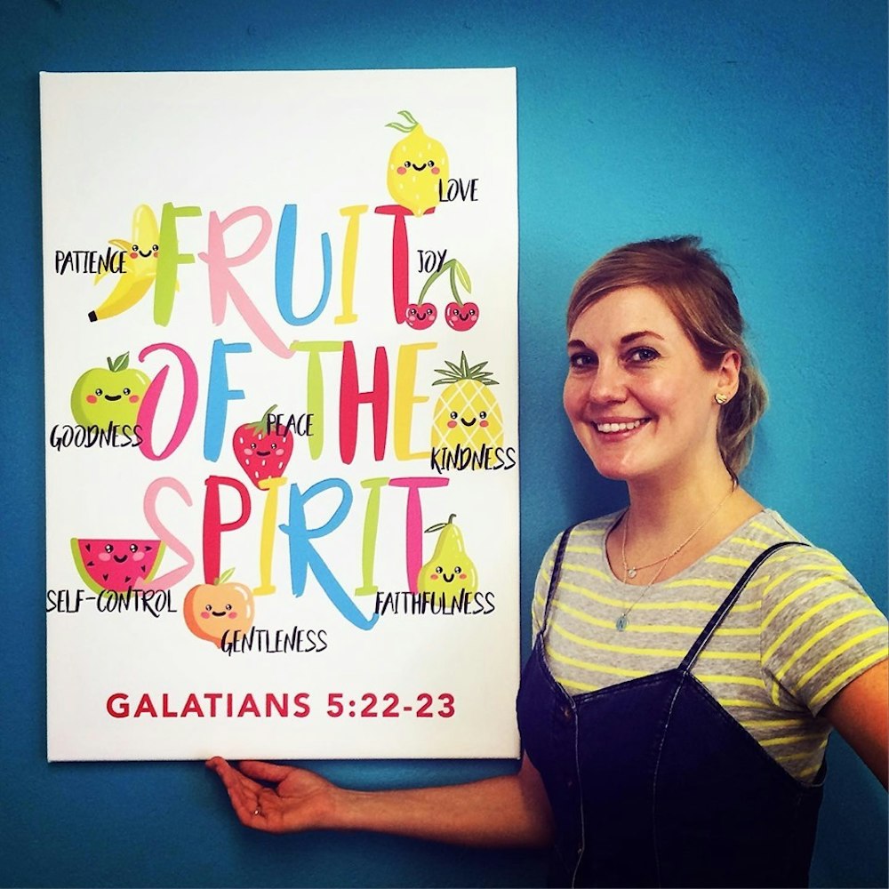 Zunelle of Nova Grace stands with her Fruit of the Spirit poster against a blue backdrop | Cheerfully Given